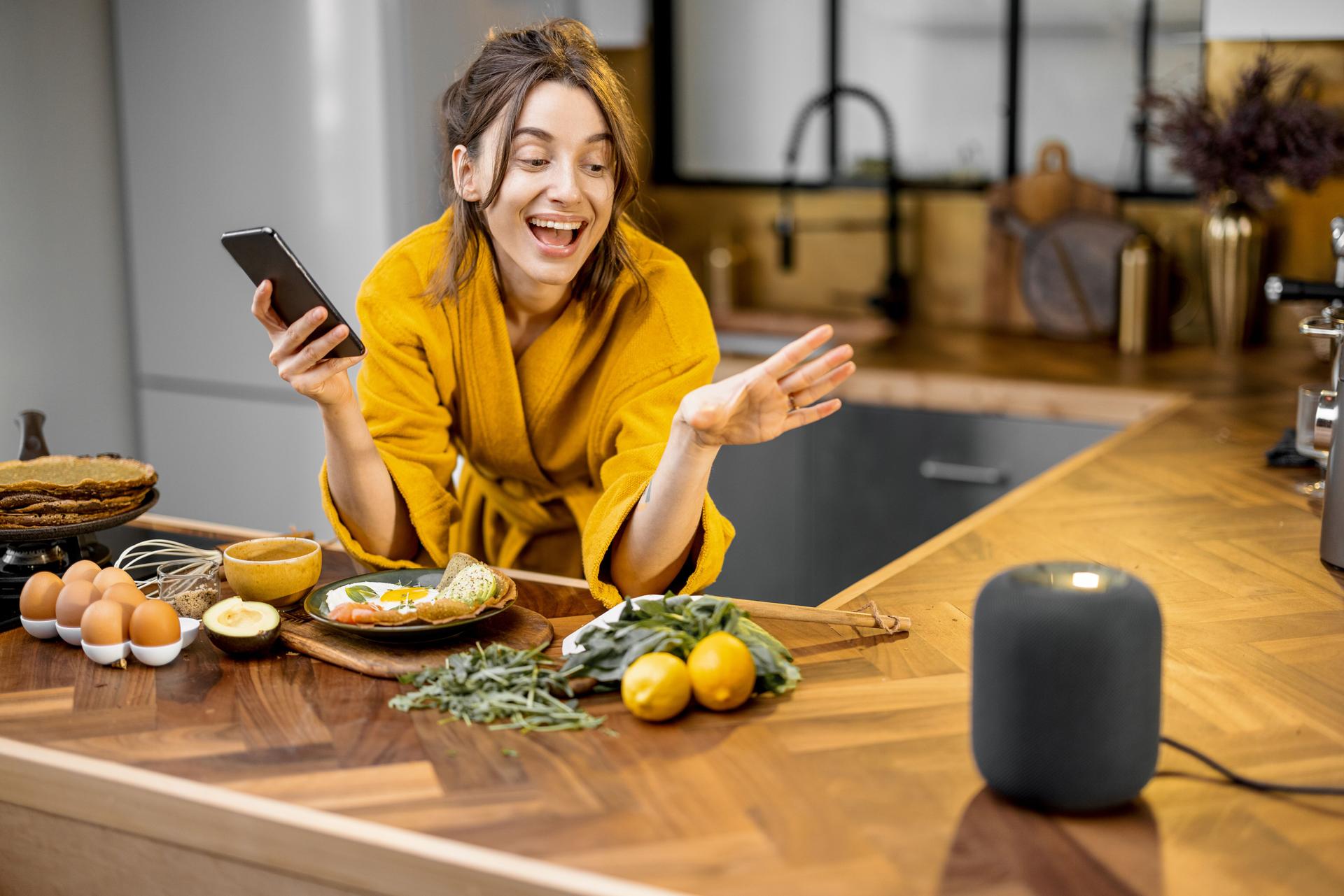 Woman speaking to a smart speaker during a breakfast at home